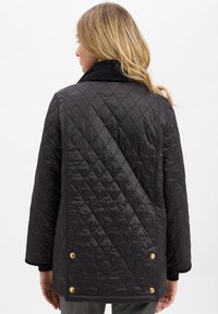 Gequilte zwarte jacket met een corduroy kraag, voorzien van gouden hardware accenten en een relaxte pasvorm, met een ruitpatroon op de stof.
