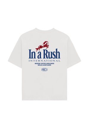 Hvid T-shirt med korte ærmer med en rød hestegrafik over stor blå tekst "In a Rush INTERNATIONAL" og mindre tekst nedenunder.