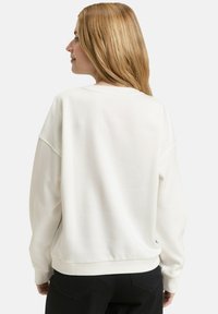 Weißes Sweatshirt aus Baumwolle mit lockerem Schnitt, gerippten Bündchen und Saum. Mit Rundhalsausschnitt und überschnittenen Schultern. Glatte Textur.
