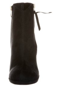 Bottine en suédine noir avec un bout arrondi, fermeture éclair latérale et un nœud décoratif en haut. Texture lisse et design minimaliste.