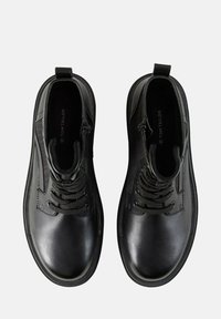 Bottes noires à la cheville en cuir lisse avec un laçage et une fermeture éclair, dotées d'un bout rond et d'accents texturés sur les côtés.
