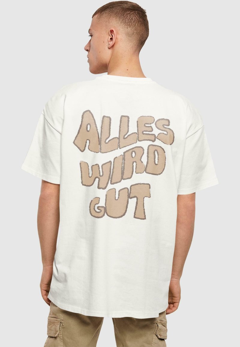 Hvid oversized t-shirt med korte ærmer, der har en stor brun tekstgrafik på ryggen med teksten "ALLES WIRD GUT." Enkel design, lavet af bomuldsmateriale.