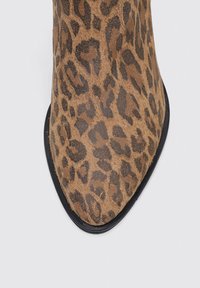 Botte de cheville en imprimé léopard avec un matériau texturé semblable à du daim et un bout pointu. La semelle noire accentue le design.