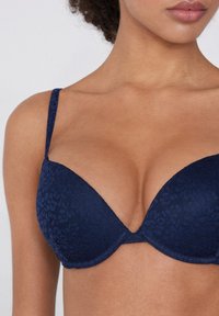 Navy blue padded bra with a floral texture, thin adjustable straps, and a plunging neckline design, featuring seamless edges and light underwire.