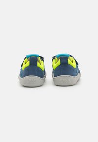 Chaussures d'enfants bleues et jaunes avec un dessus en daim, des accents en maille, une sangle à velcro et des semelles en caoutchouc grises. Nom de la marque "froddo" emboutie.