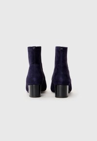 Navy suede ankle boots with a block heel, featuring a smooth texture and minimal stitching, showcasing a clean, sleek design.