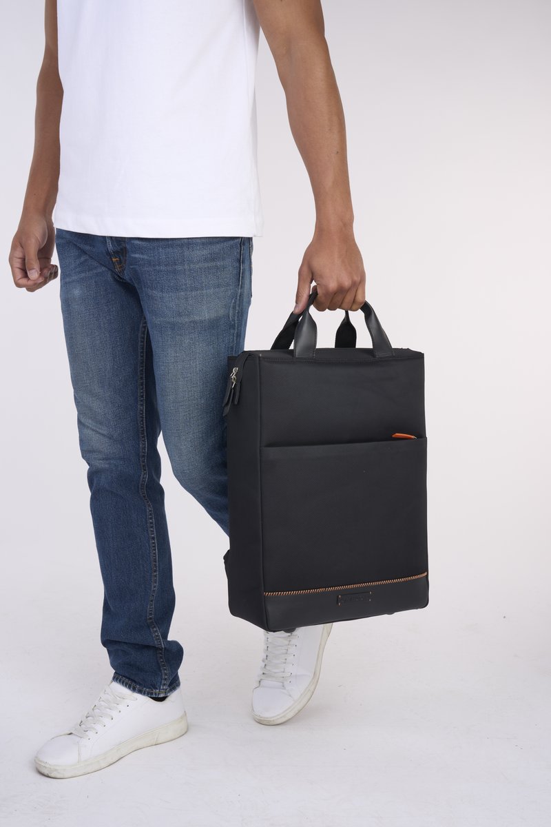 Schwarzer Stoffrucksack mit doppelten Griffen und einem Reißverschluss. Verfügt über eine Außentasche mit orangefarbenem Akzent, glatter Textur und rechteckiger Form.