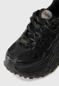 Tenis black cu un amestec de piele și material mesh, suprafață texturată și o talpă din cauciuc rezistentă, cu modele de tread proeminente.