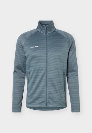 Svetlomodra jakna z zadrgo, teksturiranimi vodoravnimi črtami, visokim ovratnikom, dvema žepoma z zadrgo na straneh in logotipom "Mammut" na levi strani prsnega koša.