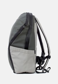 Grijze en beige rugzak met een ronde vorm, waterdicht materiaal, zwarte ritsen en een zijvak. Verstelbare straps aan de achterkant.