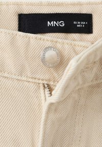 Beige denimstof met metalen knoop en deels open ritssluiting, met een zwart maatlabel met het merk MNG en maat EU 36 USA 4 MEX 3.