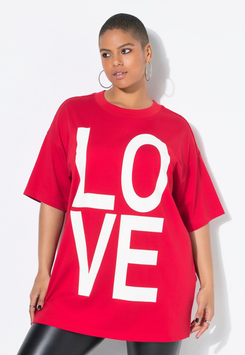T-shirt oversized in cotone rosso con grande scritta bianca "LOVE". Maniche corte e scollatura rotonda, abbinato a leggings neri lucidi.