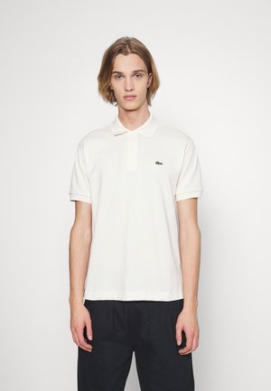 Polo skjorte i lyse beige bomuld, med klassisk krave, korte ærmer og et lille grønt broderet logo på brystet.