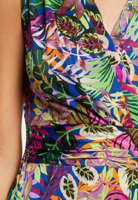 Kolorowa sukienka z żywym tropikalnym wzorem zielonych, różowych i pomarańczowych liści na niebieskim tle. Wykonana z gładkiej tkaniny.