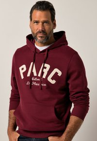 Felpa con cappuccio color bordeaux con coulisse, tasca frontale e scritte color crema con le parole "PARC" e "Nations de Plaisance." Materiale morbido in misto cotone.