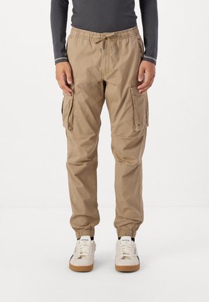 Beige cargo pants with an elastic waistband and cuffs, featuring two side pockets and a casual fit. Made from durable, lightweight fabric.