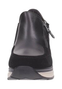 Zapato negro que combina cuero liso y ante, con un tacón bajo, cierre con cremallera en el lateral y una suela texturada para mayor agarre.