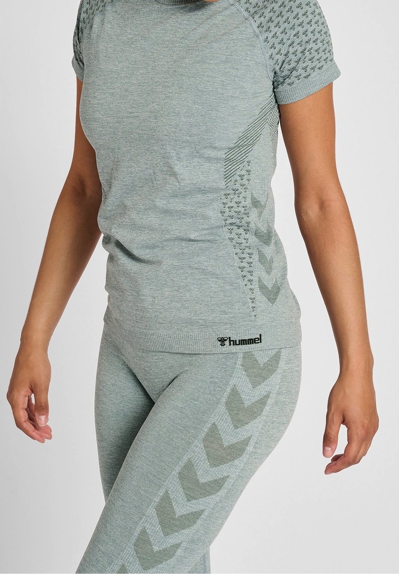 Jasnoszary komplet odzieży sportowej z dopasowanym, krótkim rękawem z teksturowanymi akcentami oraz dopasowanymi legginsami z detalami w jodełkę.