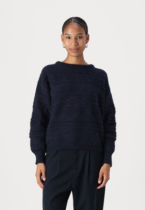 Maglione lavorato a maglia blu navy con motivi testurizzati, vestibilità ampia e orlo a coste. Presenta maniche larghe e scollatura rotonda. Materiale morbido.