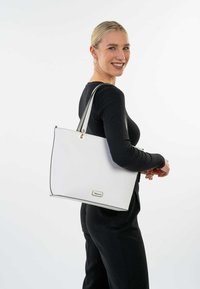Witte draagtas gemaakt van textuurstof met zwarte accenten en gouden hardware. Heeft een rechthoekige vorm en dubbele schouderbanden.