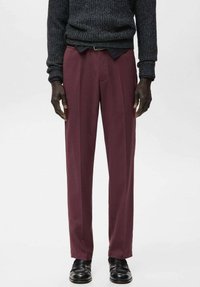 Pantalones color burdeos de corte recto, textura suave, con dos pliegues delanteros y una cinturilla lisa. Combinados con zapatos de cuero negros.