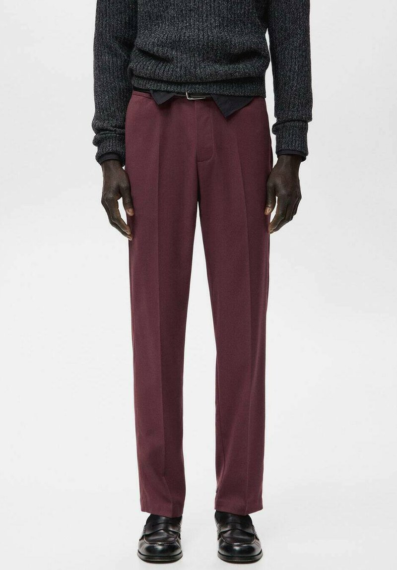 Pantalones color burdeos de corte recto, textura suave, con dos pliegues delanteros y una cinturilla lisa. Combinados con zapatos de cuero negros.