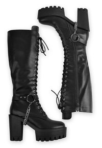 Black knee-high boots featuring a chunky heel, lace-up front, side zipper, and a chain accent with a ring detail. Made from smooth leather.