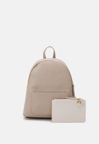 Mochila beige con un compartimento principal con cremallera, bolsillo delantero y una cartera a juego. Ambos presentan una textura suave y detalles en hardware dorado.