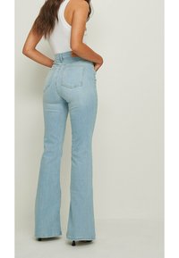 Jeans svasati di un blu chiaro realizzati in denim con vita alta, dotati di tasche posteriori e dettagli di cucitura sottili.