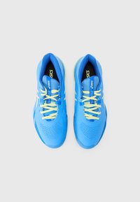 Zili sporta apavi ar acsēm augšdaļā, kontrastējošām dzeltenām šņorēm un teksturētu zoli. Uz tiem ir ASICS logo un regulējama šņorēšana.