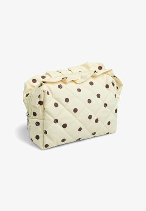 Pochette matelassée couleur crème avec des pois marron, fermeture éclair et bordure volantée tout le long du bord supérieur.