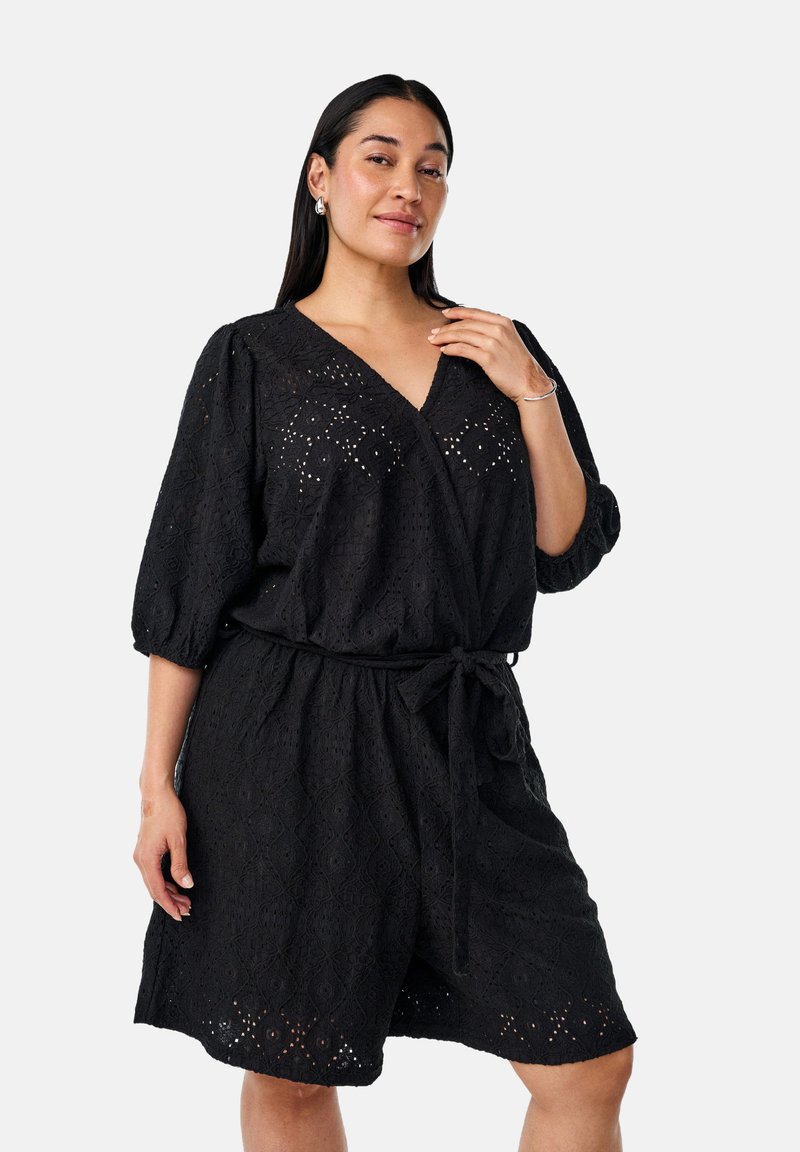 Vestido de encaje negro con diseño envolvente, mangas cortas y cintura ceñida con cinturón. Presenta un patrón de diamante y detalles de ojal a lo largo.