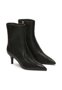 Botines de cuero negro con puntera puntiaguda y tacón de 5 cm. Cuentan con paneles elásticos laterales y cierre de cremallera en la parte posterior.