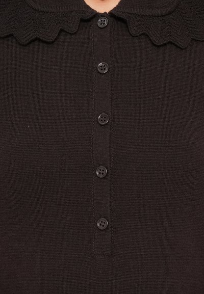 Pull en maille noire avec un col festonné et un rabat à six boutons. Présente une texture fine et un design de boutons classique.