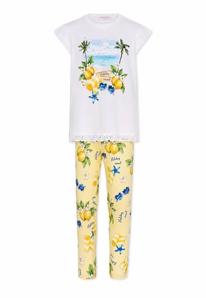 Witte top met korte mouwen met strandscène, citroenen en tekst "holiday mood", gecombineerd met gele broeken met patronen van citroenen, bloemen en zonnebrillen.