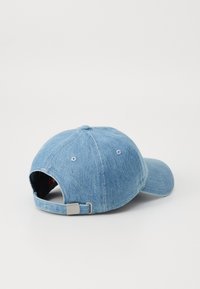 Lys blå denim baseballcap med justerbar rem, buet skygge og ventilationshuller. Blød tekstur og afslappet design.