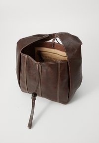 Sac en cuir marron avec une fermeture à cordon, présentant des détails de couture visibles et une poche intérieure zippée. La finition texturée ajoute du caractère.