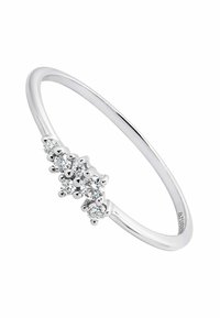 Anillo de plata con una banda delgada y tres piedras preciosas redondas y transparentes dispuestas en un racimo en el frente, exhibiendo un acabado pulido.
