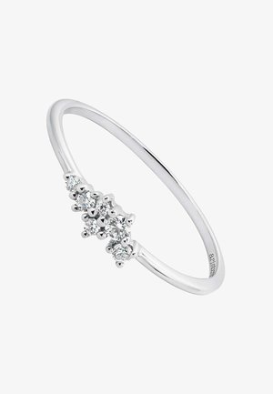 Anillo de plata con una banda delgada y tres piedras preciosas redondas y transparentes dispuestas en un racimo en el frente, exhibiendo un acabado pulido.