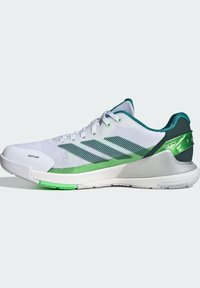 White athletic shoe with green accents, mesh upper, textured surface, and rubber sole featuring ADITUFF branding and a cushioned heel.