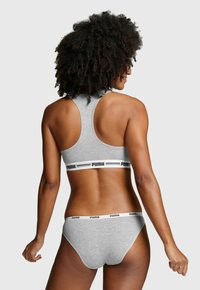 Grauer Sport-BH mit Racerback-Design und schwarzem Logo-Band; passende graue Unterwäsche mit einem ähnlichen Logo-Band. Glattes, dehnbarem Material.