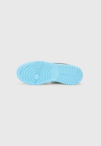 Nike sneaker sole with a blue rubber outsole, featuring circular and horizontal tread patterns for traction. Minimalist design with branding.