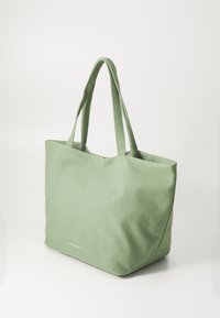 Sac en toile vert avec deux longues anses, forme rectangulaire, surface texturée et petit logo imprimé sur le bord inférieur.