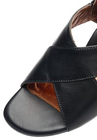 Sort lædersandal med brede krydsremme og en brun læderinderside, åben tå-design.