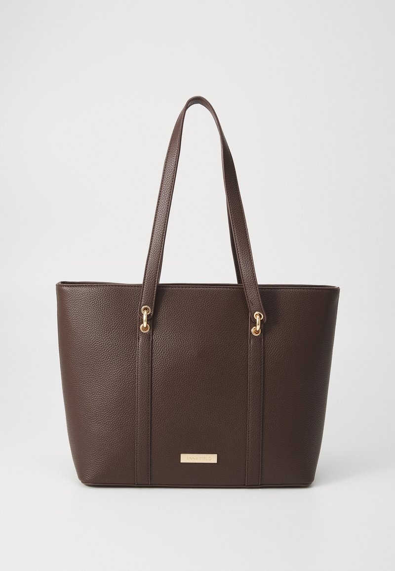 Sac cabas en cuir texturé marron foncé avec doubles anses épaules et détails dorés, forme rectangulaire, petite plaque de marque à l'avant.