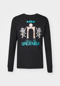 Black long-sleeve t-shirt featuring a graphic of a basketball, an arch, and two lions. Text reads "Strive For GREATNESS" in turquoise.