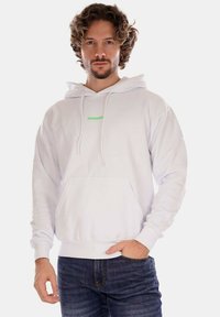 Felpa bianca realizzata in morbido tessuto, caratterizzata da una tasca frontale, cappuccio con cordini e un piccolo logo verde "PROPAGANDA" sul petto.
