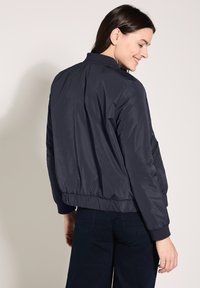 Marineblaues Bomberjacke aus glattem, leichtem Material. Mit elastischen Bündchen und Saum, entspannter Passform und ohne sichtbare Beschläge.