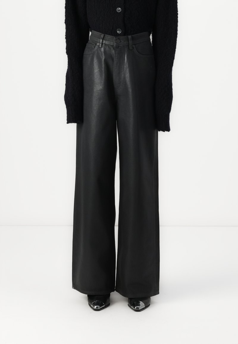 Pantalon en cuir noir à jambes larges, texture lisse, taille haute, et design classique à cinq poches. Associé à un pull en maille texturée noir.
