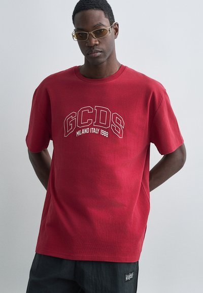 T-shirt en coton rouge avec le texte blanc "GCDS MILANO ITALY 1988", manches courtes et coupe décontractée. Texture douce, design simple à col rond.
